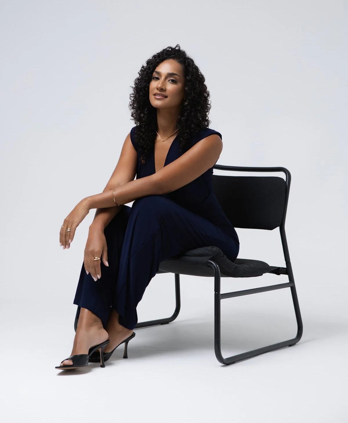 Anna Lobo sentada numa cadeira, vestida de azul escuro, sobre fundo claro